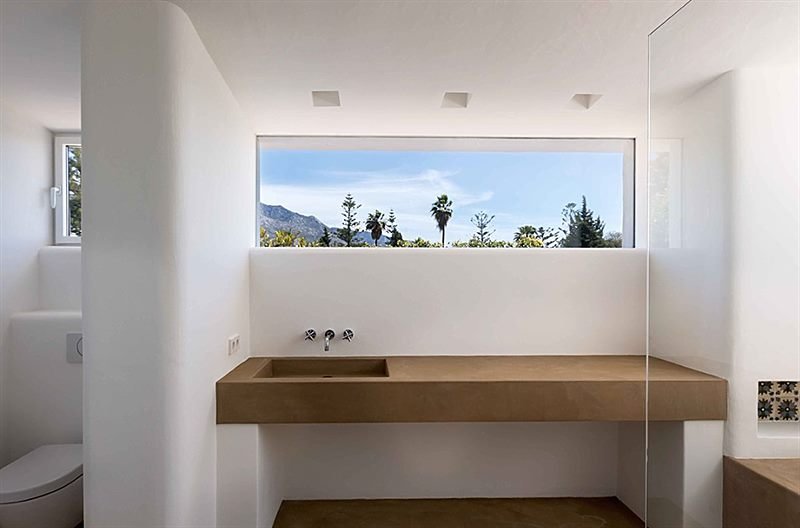 Baño con lavabo de obra y ventana panorámica a la sierra