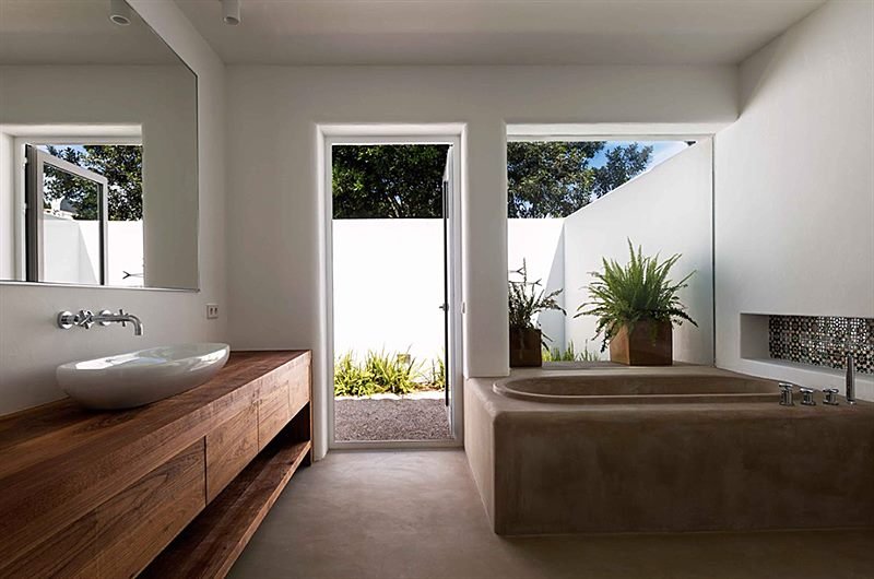 Baño con bañera de obra, encimera de madera maciza y patio ajardinado