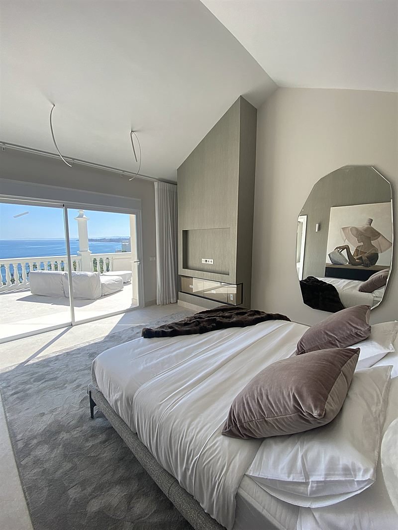 Dormitorio en suite con cabecero de listones de madera y vistas al mar