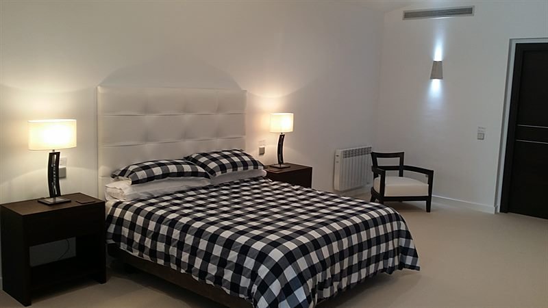 Dormitorio principal con cabecero capitoné y climatización por conductos