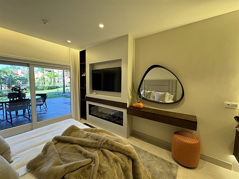Dormitorio principal con chimenea, espejo de diseño y vistas al jardín